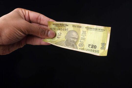 Indian 20 Rupee Banknote Held in Hand Against Black Background