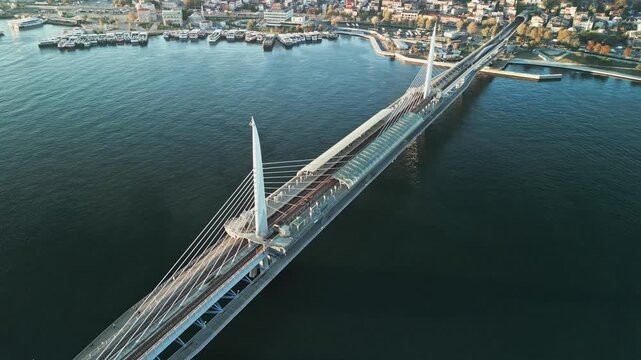 Turkey, Istanbul 06 10 2025: 4K drone video moving backward starting from metro station to reveal full Golden Horn Metro Bridge framed diagonally across sea water.