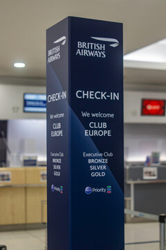 A tall British Airways advertising direction stand in standard company livery located in Belfast City Airport