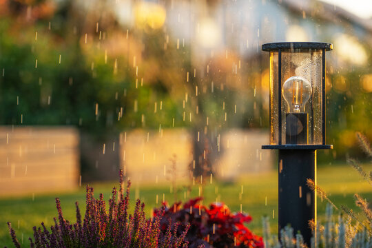 Garden post lamp among falling water droplets