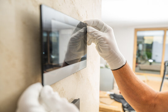Gloved hands holding a wall mounted glass panel