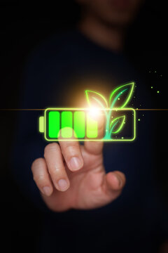 Finger touching glowing green battery hologram growing small leaves, representing activation of renewable energy, clean power storage technology, and eco-friendly ESG solutions, Vertical stock photo.