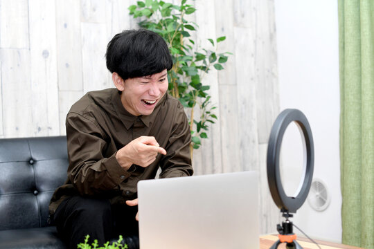 A young Asian man getting angry and arguing back at haters during a live stream.