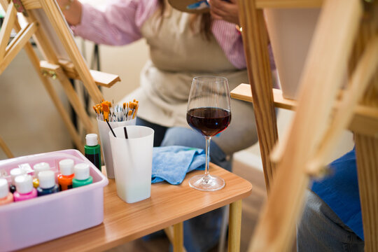 People enjoying a relaxed adult art class with wine and painting supplies for creative leisure activity