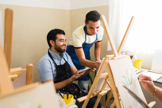 Men enjoying an adult art class, painting on canvases with easels, learning new skills and expressing creativity