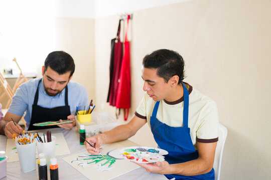 Two adult men learning to paint in an art class, developing creativity and new hobbies during leisure time