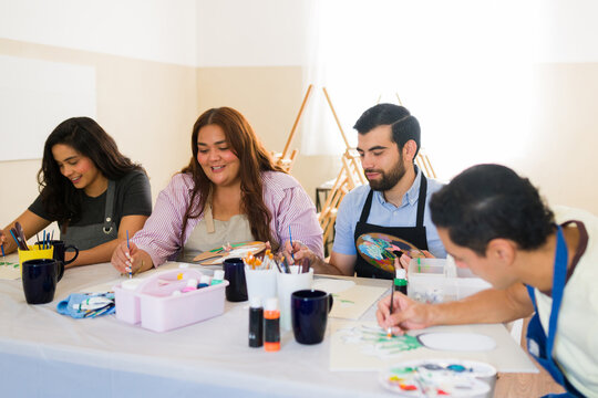 Diverse adults painting together at an art class, enjoying creative hobbies and learning new skills in a workshop