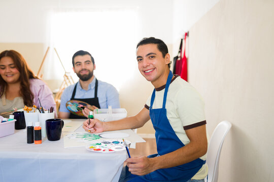 Smiling man painting during an adult art class, enjoying a creative workshop with fellow students