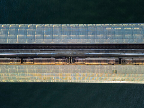 Turkey, Istanbul 06 10 2025: Symmetrical top-down aerial drone photo of Halic Metro Station on Golden Horn bridge with train stopped at platform, framed horizontally over sea water.