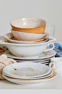 Stack of dirty used dishes, bowls, plates and cups waiting to be washed in a domestic kitchen
