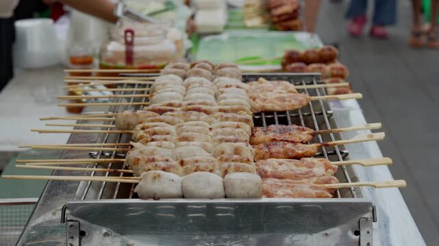 Variety of skewered street food cooking on a grill