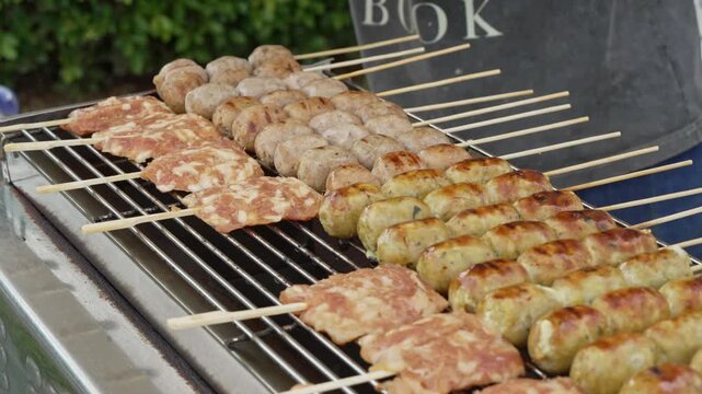 Assorted skewered street food grilling on a barbecue