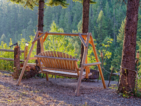 A swinging wood bench is lit by the early morning sun in the mountains of western Montana, USA