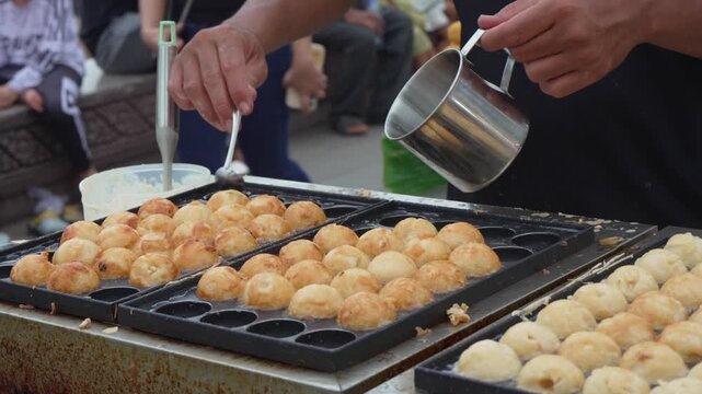 Vendor cooking golden round snacks in a street food griddle