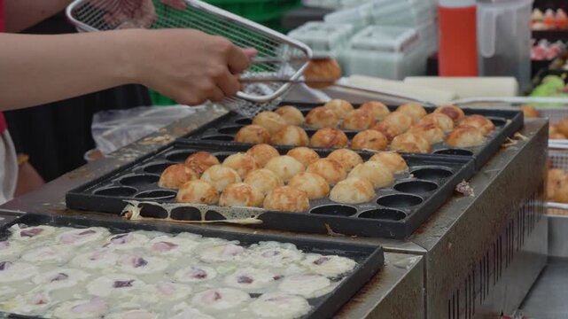 Street food vendor scooping batter into a round griddle pan