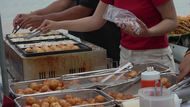 Street vendor preparing fresh round snacks on a griddle