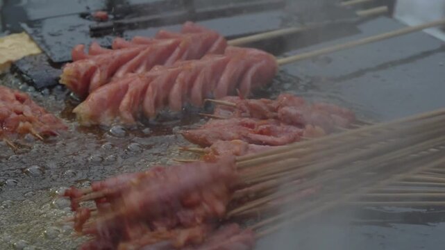 Close up of sausage skewers grilling on a street food barbecue