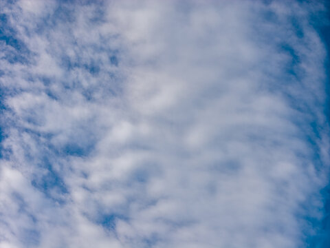 A soft band of white and pale gray cloud crosses the center of the sky between narrow openings of blue at the sides. The open sky offers a calm backdrop featuring soft blue tones throughout the frame.