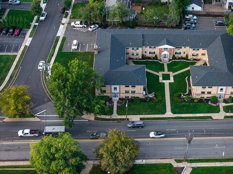 Aerial drone view of tree-lined suburban intersection, nearby homes, and local streets in Bayberry Park, New Rochelle, New York