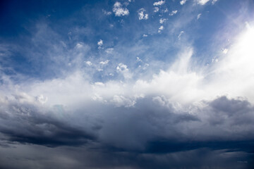 Obraz premium Dramatic storm clouds building in blue sky with bright sunlight breaking through