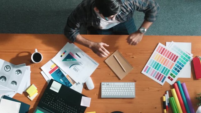Top view of smart businessman hand choosing color palettes while designing logo graphic. Aerial view of professional interior designer design and select color theme by using color palettes. Symposium.