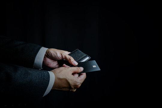 Businessman Holding Credit Card and Wallet on Black Background with Copy Space