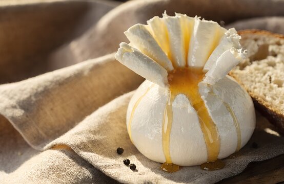 A ball of burrata cheese carefully opened and arranged to fan out like flower petals, the creamy interior spilling slightly at the center where a generous pool of honey has been poured