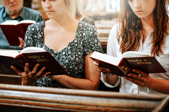Women reading Holy Bible during quiet church service
