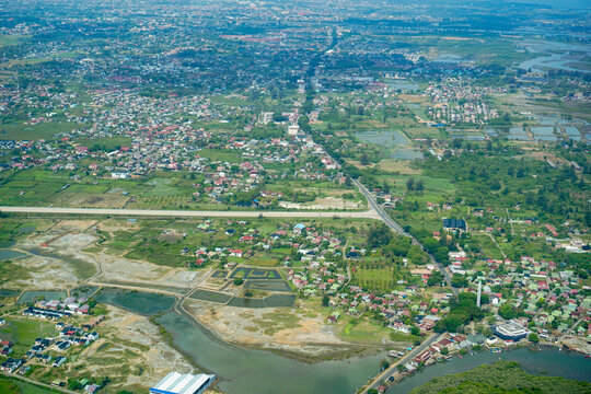 Banda Aceh and Aceh Besar aerial view from above. Aerial view of Aceh Besar landscape, including residential areas, green fields, and a new toll road under construction. Looking towards the ocean.