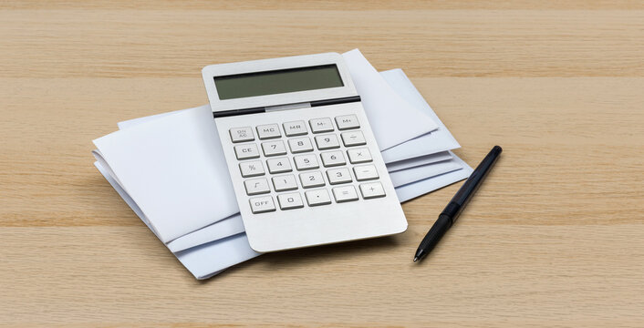 Calculator and Pen on Stack of Envelopes for Home Finance Planning