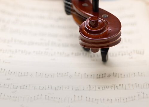 Top View Macro of Wooden Violin Scroll on Music Notes