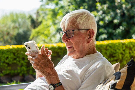 profile of elderly man texting on smart phone at sunset outdoors