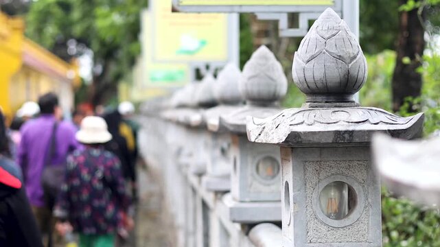 Line of traditional stone lanterns with people walking along a path.