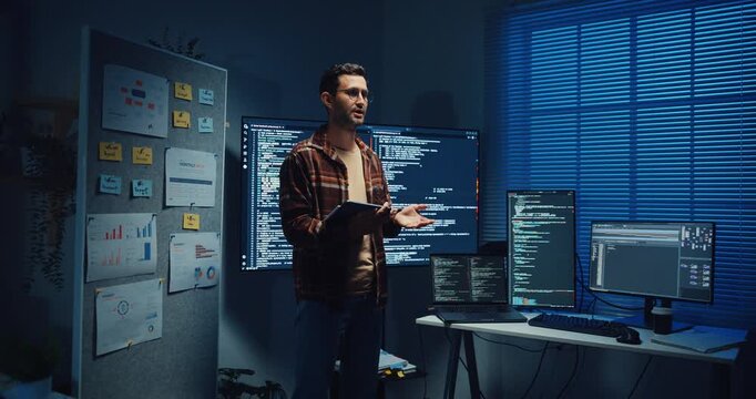 Confident Caucasian male engineer presents software strategy during late night work in office. Experienced tech consultant expertise, Innovative startup leader, Professional online conference concept.