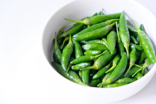 Fresh green bird's eye chilies or cabe rawit hijau in a white bowl for culinary ingredients