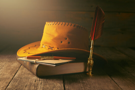Vintage still life with old book, pen, feather and hat
