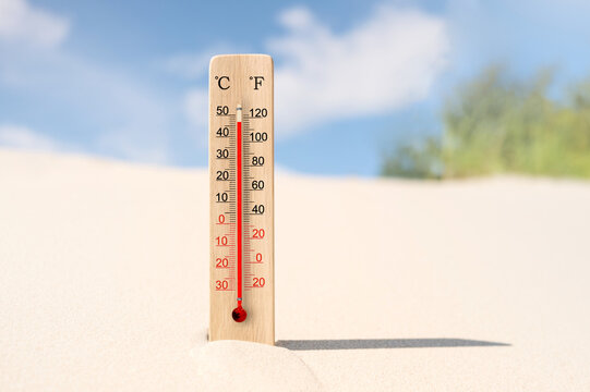 Wooden celsius and fahrenheit scale thermometer in the sand. Air temperature plus 47 degrees