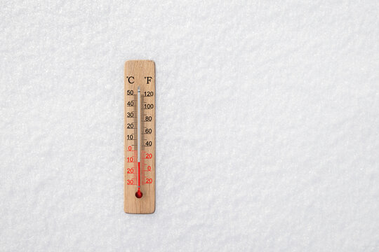 White celsius and fahrenheit scale thermometer in snow. Ambient temperature minus 10 degrees celsius