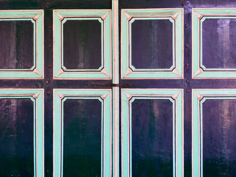 A detailed architectural crop of an antique wooden door showing ornate rectangular paneling, vintage textures, and traditional colors in a royal Indonesian palace