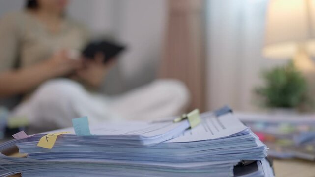 Stack of Financial Documents with Woman Reviewing Paperwork at Home