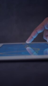 Close up of finger swiping on tablet screen showing glowing line graph motion