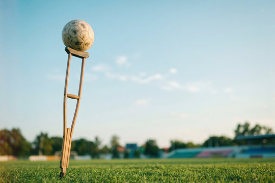 Soccer Ball Balanced on Crutch at Empty Field, Sports Injury Recovery and Comeback Concept