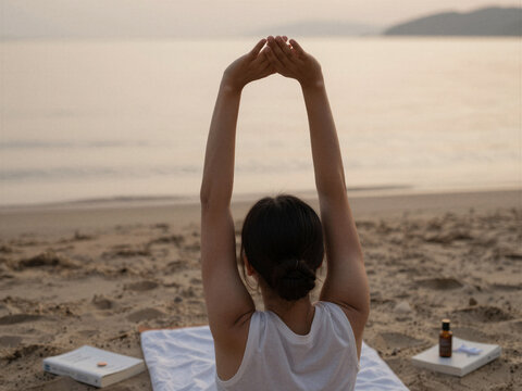 Woman practicing yoga and meditation on a sandy beach at sunset with wellness spa products