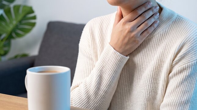 Woman with Sore Throat Holding Neck next to Hot Drink Mug &ndash; Respiratory Illness Concept Banner