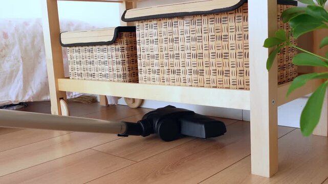 Cleaning under furniture using a vacuum cleaner in a room