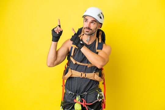Young caucasian rock climber man isolated on yellow background pointing with the index finger a great idea