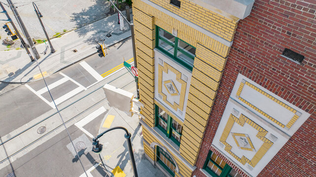 Aerial view of a historic brick building with decorative yellow accents and green historic architecture urban street decorative facade city corner exterior design paved road