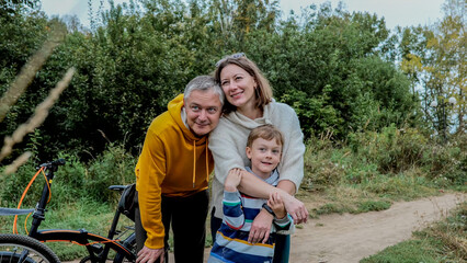 Obraz premium Smiling family of three embracing near bicycle on green trail, with family, parent, child, father detail, showing mother, boy, smile, hug context, with clear visible detail, showing commercial