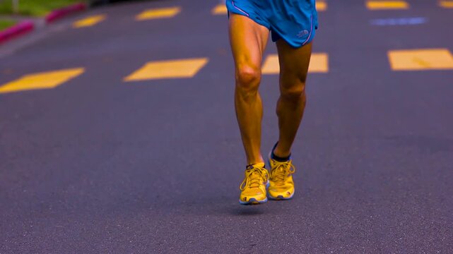 close up of ultra marathon athletes legs as they run on the asphalt