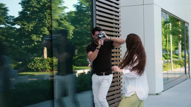 Happy woman acting and dancing in front of a man recording with a retro super 8 film camera